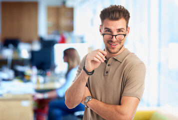 Fototapeta premium Young man standing in a modern office and looking at camera