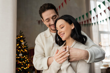 Happy couple enjoying Christmas together at home near a beautifully decorated tree