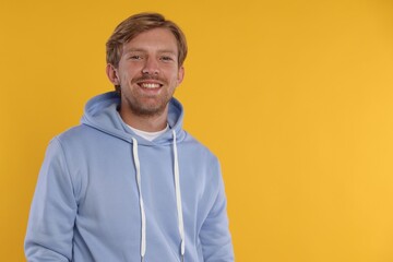 Portrait of happy man on orange background, space for text
