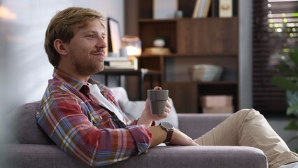 Man with cup of drink on sofa at home