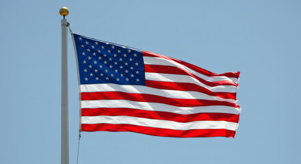 Obraz premium American flag waving brightly against clear blue sky 