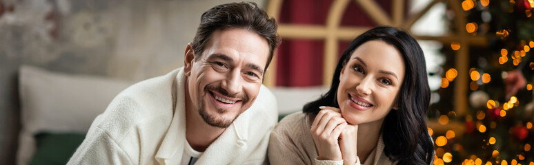 Obraz premium Couple joyfully celebrating Christmas together beside a beautifully adorned tree