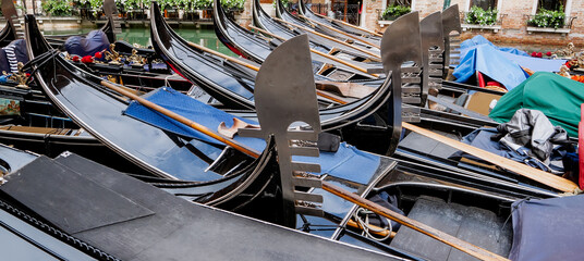 A Cluster of Traditional Black Gondolas Moored Side-by-Side in a Venetian Canal, Highlighting the...
