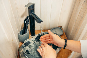 Hands washing with soap at a modern stone sink. The setting is serene and minimalistic, ideal for relaxation during a vacation escape.