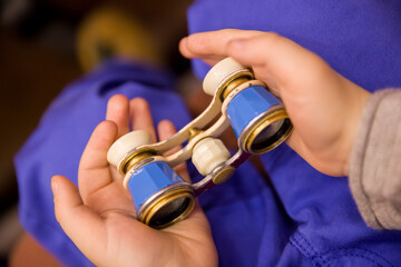 The old theater binoculars are in the hands of the child. Selective soft focus