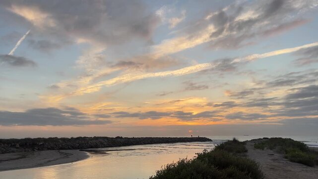 A beautiful sunset over the ocean with a small island in the distance. The sky is filled with clouds and the water is calm