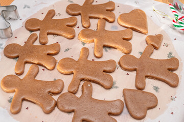 Making Christmas cookies - gingerbread men, woman is cutting out the cookies with molds.