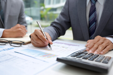 Businessman calculating finances with pen and documents at an office desk