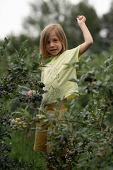 a girl with blonde hair picked one berry and wants to throw it