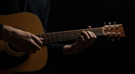 Fototapeta premium Person plays an acoustic guitar with a dark background.