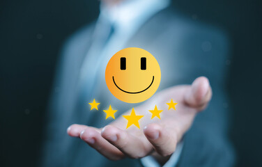 Businessman holding a glowing smiley face with five stars, representing customer satisfaction, feedback, service quality, review rating, and positive user experience in business.