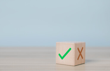Wood cube with check mark and cross sign on table, symbolizing decision making, right and wrong choice, evaluation, approval process, and quality control in business. yes or no concept