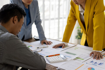 Stressed Asian businessman having problems at work with coworkers discussing about charts and graphs.