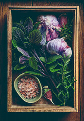 Fresh organic herbs, salt and garlic on rustic wooden tray. Top view. Natural food ingredients