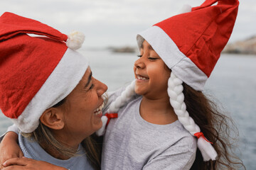 Happy latin mother and daughter celebrating Christmas together outdoor - Mom and female child...