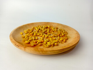 Soybeans on a wooden plate, isolated on white background.