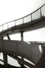 Modern architectural detail of a curved pedestrian bridge captured in black and white, emphasizing geometry, lines, and minimalism