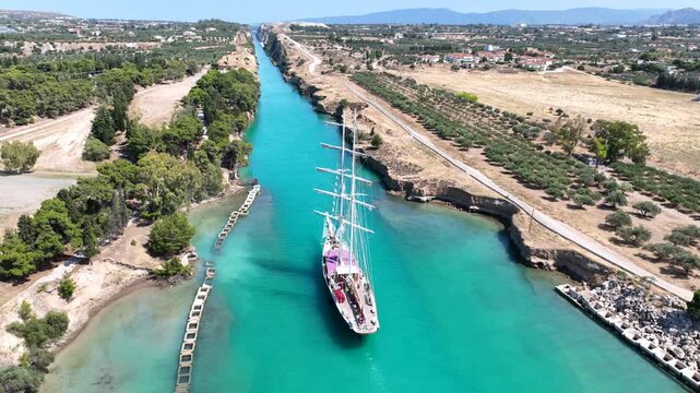 Aerial drone cinematic video of classic sailing boat crossing narrow Corinth canal of Isthmus from West submersible bridge and narrow opening of Corinthian gulf to Saronic gulf, Loutraki, Greece