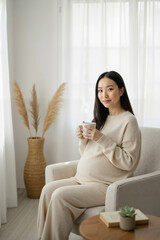Pregnant woman relaxing with cup of tea in cozy living room, maternity lifestyle concept