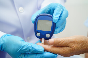 Asian doctor using digital glucose meter for check sample blood sugar level to treatment diabetes.