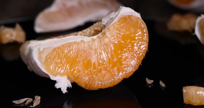 half of an orange citrus on a black mirror , ripe sweet and juicy citrus is reflected on the black surface