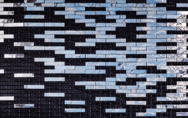 a modern, geometric tile wall featuring a pattern of rectangular tiles. The tiles are arranged in a...