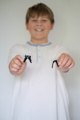 Smiling child showing two removable orthodontic retainers in hands. Dental care, orthodontics, healthy teeth and pediatric dentistry concept.

