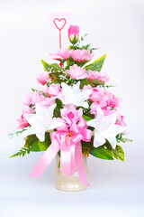 Elegant bouquet of artificial pink and white flowers arranged in  ceramic vase with pink ribbon and heart-shaped card. Perfect for romantic, congratulations or home decoration.