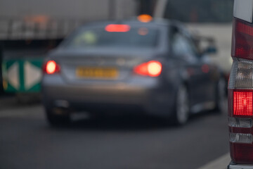 Blurred car with brake lights in traffic on urban road