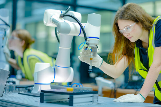Two female engineering students in a high-tech university lab collaborate on a robotics project, learning hands-on programming skills for the future of industrial automation.