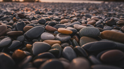 Obraz premium Tranquil beach pebbles glistening at sunset with warm, earthy hues and smooth texture