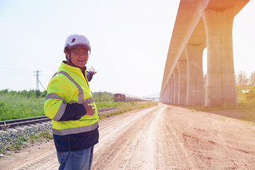 Obraz premium Asian architect engineer wearing safety uniform surveying and working at building structure checking blueprints construction site road general job details business concept architecture street
