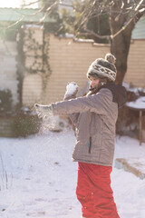 Boy playing snowball fight outdoors on sunny winter day