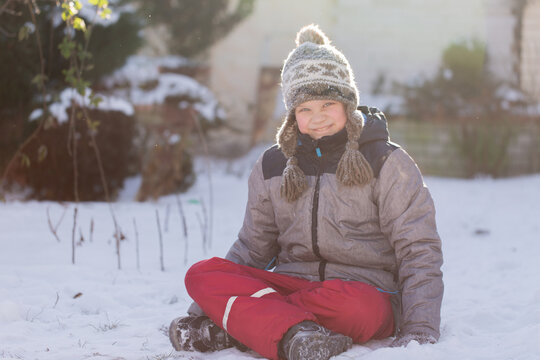 Boy sitting on snow smiling warmth in cold day outdoor childhood happiness horizontal