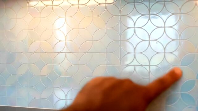 Close-up of a hand pointing at a colorful tiled wall in a modern kitchen