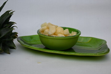 Pineapple or Ananas comosus slices on white background. It is a tropical plant with an edible fruit. It is plant in the family Bromeliaceae. Pineapple pieces in a bowl ready to eat.
