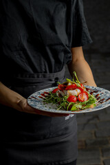 A girl in dark clothes holds a plate of food in her hands