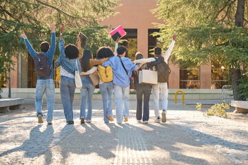 Group of diverse university students walking arm in arm, raising hands in celebration on campus
