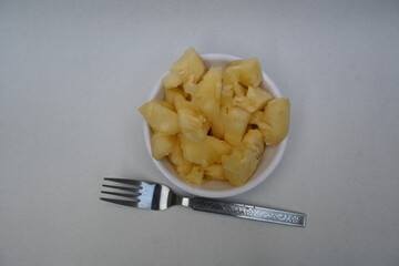 Pineapple or Ananas comosus slices on white background. It is a tropical plant with an edible fruit. It is plant in the family Bromeliaceae. Pineapple pieces in a bowl ready to eat.