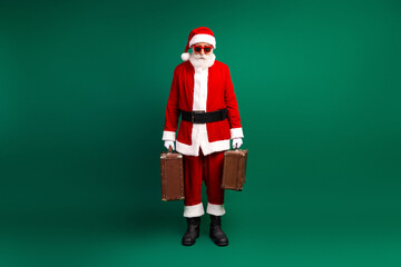 Santa Claus with Suitcases in Bold Red Costume on Green Background, Showing a Fun and Seasonal Holiday Attitude
