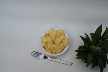 Pineapple or Ananas comosus slices on white background. It is a tropical plant with an edible fruit. It is plant in the family Bromeliaceae. Pineapple pieces in a bowl ready to eat.