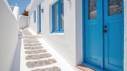 Charming pathway leads to bright blue door, surrounded by whitewashed walls and stone accents, evoking serene atmosphere
