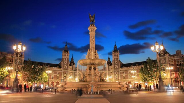 Static wide-angle time-lapse video of Madrid's iconic Cibeles Fountain and grand architecture as sky transitions from golden hour to night, with vehicle light trails. Majestic urban spectacle