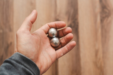 CNC spheres in a man's hand, daylight highlights their form. A symbol of two poles and the force that holds them. A vision of power, balance, and precision.