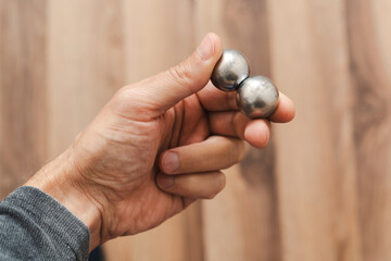 CNC spheres in a man's hand, daylight highlights their form. A symbol of two poles and the force that holds them. A vision of power, balance, and precision.