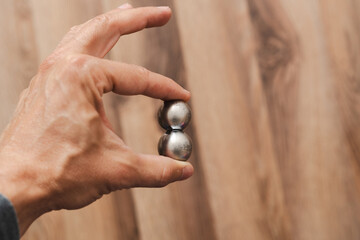 CNC spheres in a man's hand, daylight highlights their form. A symbol of two poles and the force that holds them. A vision of power, balance, and precision.