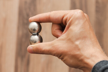 CNC spheres in a man's hand, daylight highlights their form. A symbol of two poles and the force that holds them. A vision of power, balance, and precision.