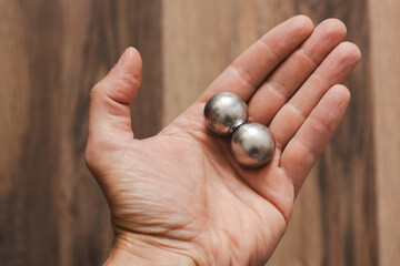 CNC spheres in a man's hand, daylight highlights their form. A symbol of two poles and the force that holds them. A vision of power, balance, and precision.
