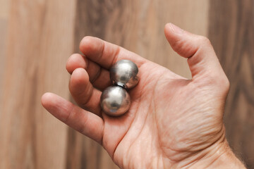 CNC spheres in a man's hand, daylight highlights their form. A symbol of two poles and the force that holds them. A vision of power, balance, and precision.