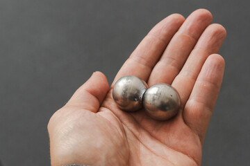 CNC spheres in a man's hand, daylight highlights their form. A symbol of two poles and the force that holds them. A vision of power, balance, and precision.